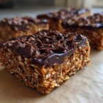 A close-up, featured image of a thick, chewy homemade protein bar topped with melted chocolate and chocolate shavings.
