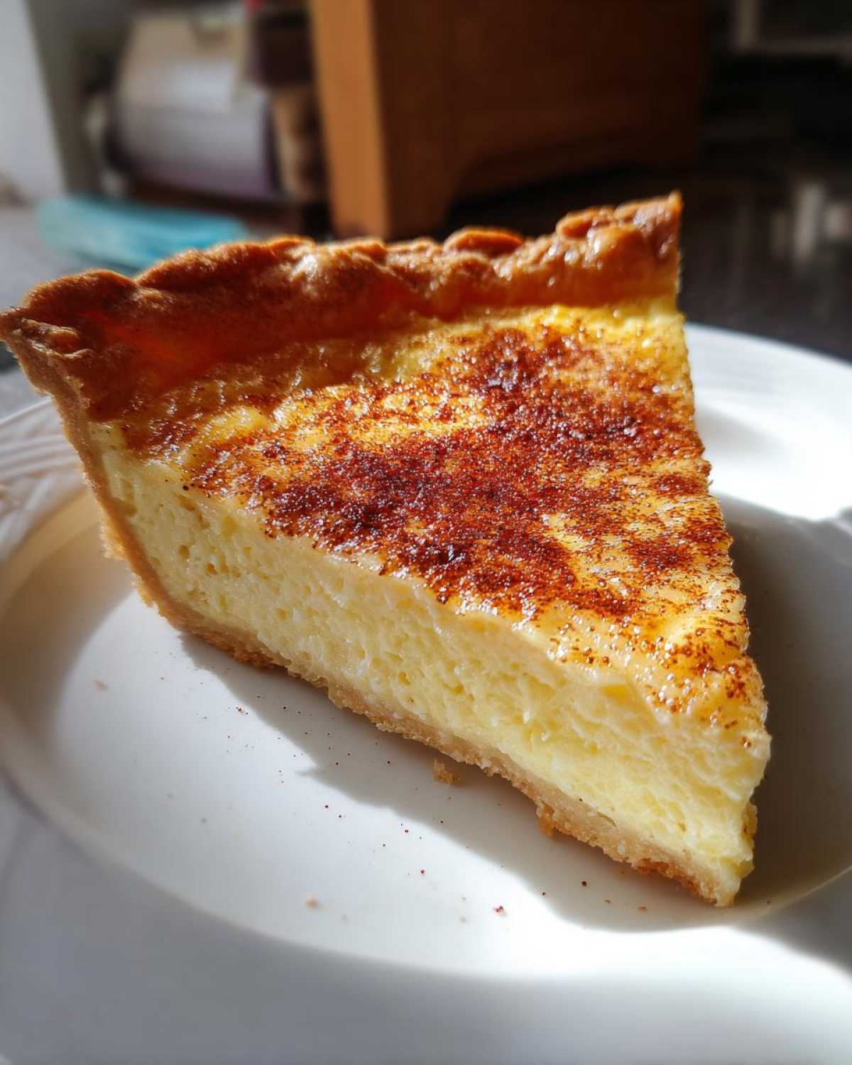 A close-up slice of amazing custard pie with a golden crust and sprinkled cinnamon on top.