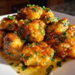 Close-up of golden brown, glazed chicken bites topped with fresh chopped parsley.
