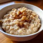 Close-up of creamy apple cinnamon oatmeal topped with cooked apple chunks and cinnamon spice.
