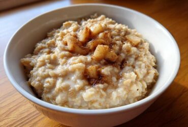 Close-up of creamy apple cinnamon oatmeal topped with cooked apple chunks and cinnamon spice.