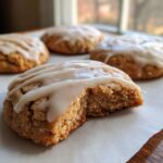 A chewy maple cookie with a bite taken out, showing the soft interior and white maple glaze.