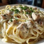 Close-up of rich, creamy chicken alfredo pasta tossed with fettuccine and topped with fresh parsley.