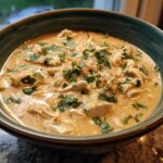 A close-up of a bowl filled with creamy, shredded keto white chicken chili, garnished with fresh cilantro.
