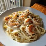 Close-up of creamy shrimp alfredo pasta with large seasoned shrimp and parsley garnish.