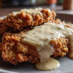 Two pieces of crispy, golden brown chicken fried steak smothered in rich, creamy white pepper gravy.