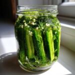 Close-up of fresh cucumbers packed vertically in a glass jar with dill and garlic for making refrigerator pickles.