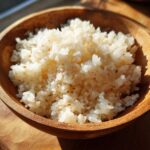 Close-up of fluffy, perfectly seasoned sushi rice served in a warm wooden bowl.