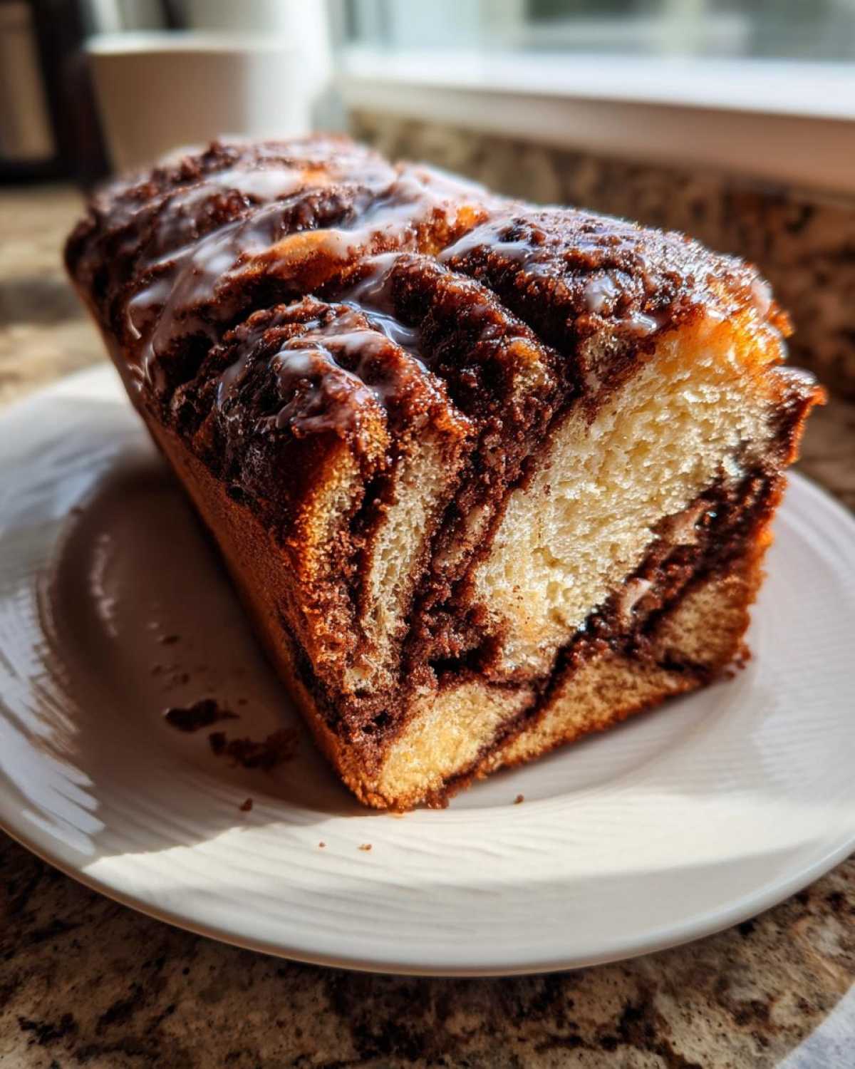 A slice of homemade chocolate babka loaf, showing rich chocolate swirls and a sweet glaze on top.