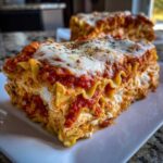 Close-up of a thick slice of instant pot lasagna showing layers of pasta, ricotta, and rich tomato sauce topped with melted mozzarella.