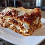 A thick, layered slice of instant pot lasagna featuring rich meat sauce and creamy ricotta cheese, topped with melted mozzarella.