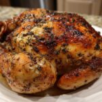 A perfectly cooked, whole roasted chicken with deeply browned, crispy skin seasoned with herbs.