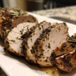 Close-up of sliced, juicy slow cooker turkey breast coated in herbs and rosemary.
