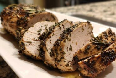 Close-up of sliced, juicy slow cooker turkey breast coated in herbs and rosemary.