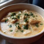Close-up of a bowl of creamy keto white chicken chili topped with melted cheese and fresh cilantro.