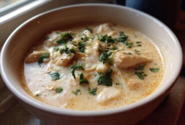 Close-up of a bowl of creamy keto white chicken chili topped with melted cheese and fresh cilantro.