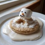 A close-up of one of the melted snowman cookies, featuring a melting marshmallow head on a sugar cookie base covered in white icing.