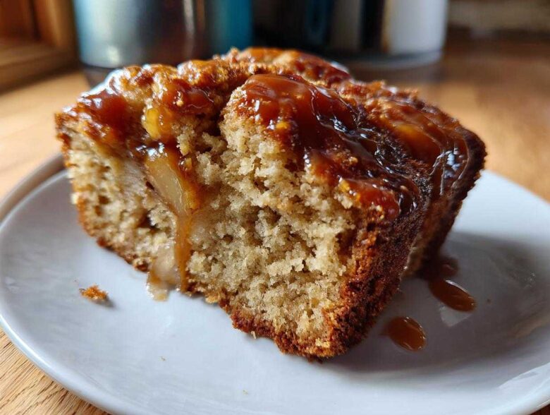 Close-up of a moist slice of apple dapple cake topped with gooey caramel sauce dripping down the side.