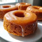 Close-up of a moist baked pumpkin donut covered in a dripping brown sugar glaze.