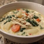 Close-up of a hearty bowl of Olive Garden Chicken Gnocchi Soup with shredded chicken, carrots, spinach, and gnocchi.