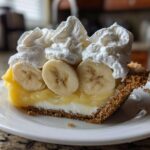 A decadent slice of banana cream pie recipe featuring a graham cracker crust, creamy filling, sliced bananas, and whipped cream.