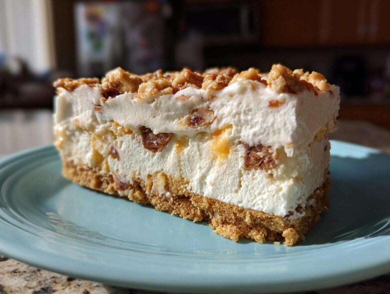 A thick slice of no-bake christmas tree cheesecake with a graham cracker crust and crunchy nut topping.