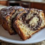 Two slices of moist chocolate babka bread, featuring a rich swirl of chocolate filling and topped with a white vanilla glaze.