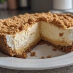 A slice removed from a creamy peanut butter pie showing the graham cracker crust and crumb topping.