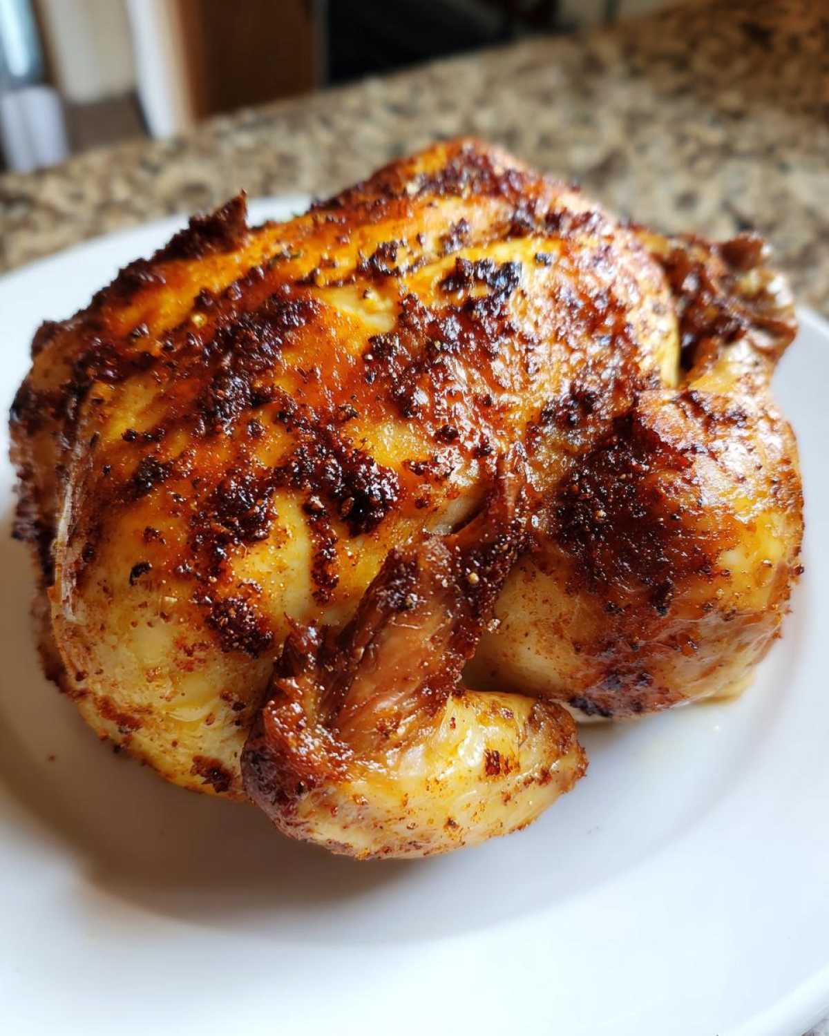 A beautifully roasted, crispy-skinned air fryer whole chicken resting on a white plate.