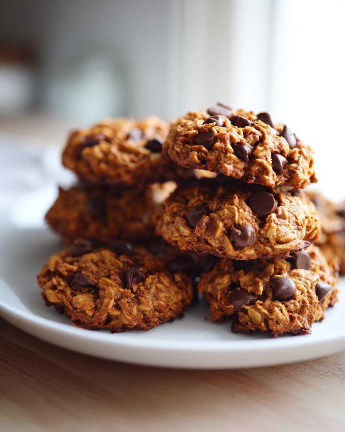 A close-up stack of homemade breakfast cookie loaded with chocolate chips on a white plate.