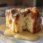 A decadent square of bread pudding drenched in thick vanilla sauce, showcasing the texture of the amazing bread pudding.