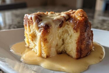 A decadent square of bread pudding drenched in thick vanilla sauce, showcasing the texture of the amazing bread pudding.