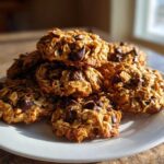 A stack of golden brown breakfast cookie treats loaded with oats and chocolate chips on a white plate.