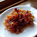A close-up of rich, dark brown caramelized onions piled on a small white dish.