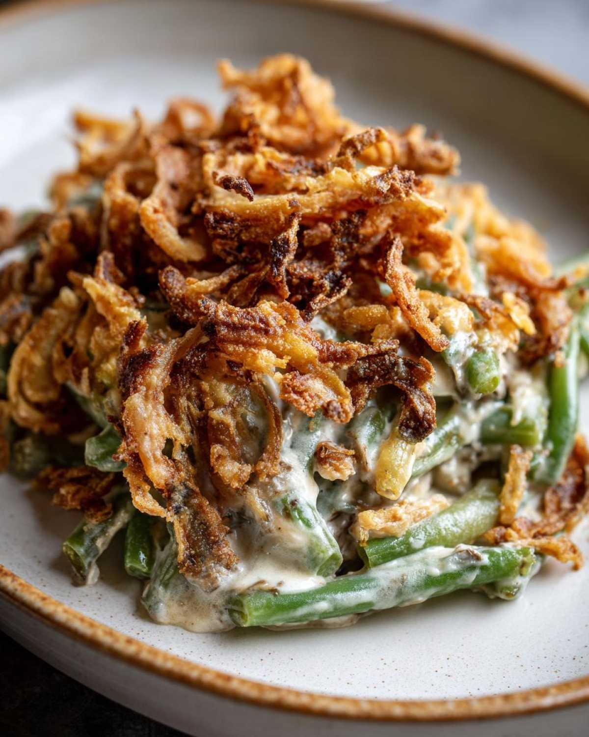 A close-up serving of amazing green bean casserole topped generously with crispy fried onions.