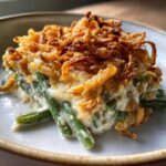 Close-up of a creamy slice of green bean casserole topped generously with crispy fried onions.