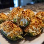Close-up of baked Jalapeño poppers stuffed with creamy cheese and topped with golden brown breadcrumbs.