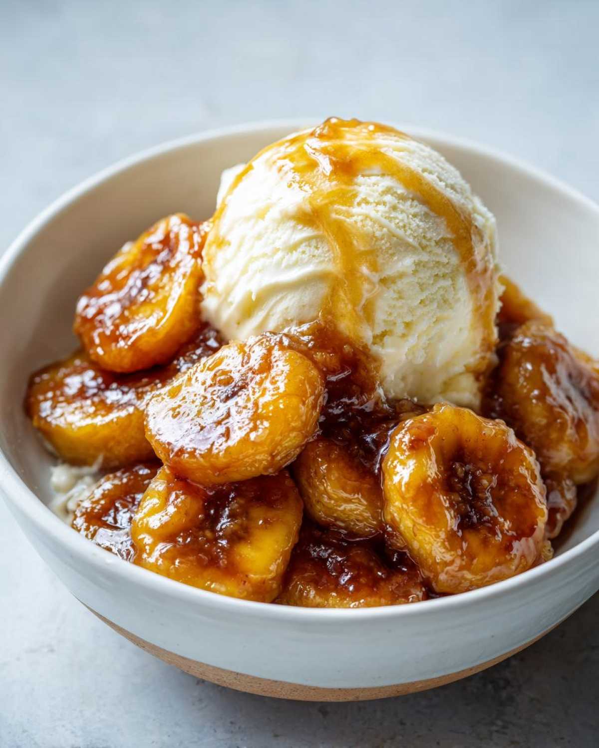 Close-up of warm, caramelized bananas foster served with a scoop of vanilla ice cream.