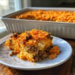 A hearty serving of Dorito Casserole topped with ground beef and crushed orange chips on a white plate.