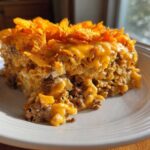 A hearty slice of Dorito Casserole featuring ground meat, cheesy sauce, and a crunchy Dorito chip topping.