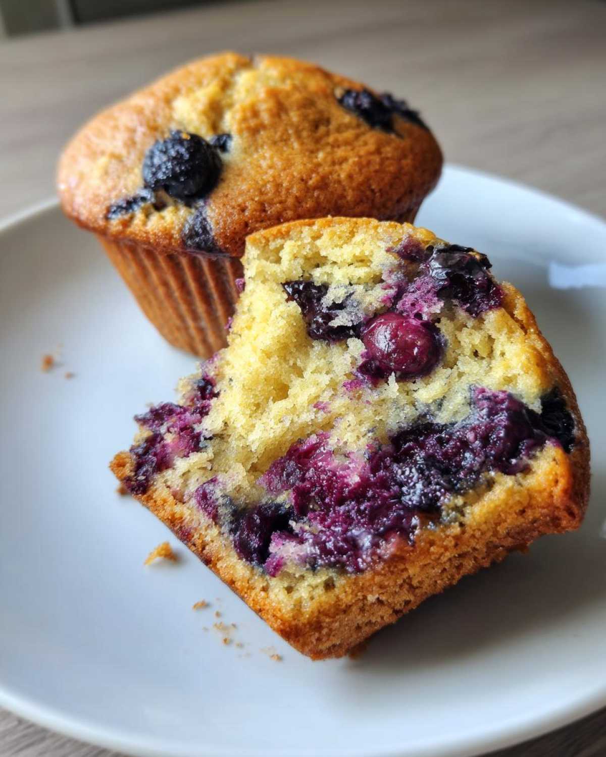 Close-up of a blueberry protein muffin cut in half showing the moist, berry-filled interior.
