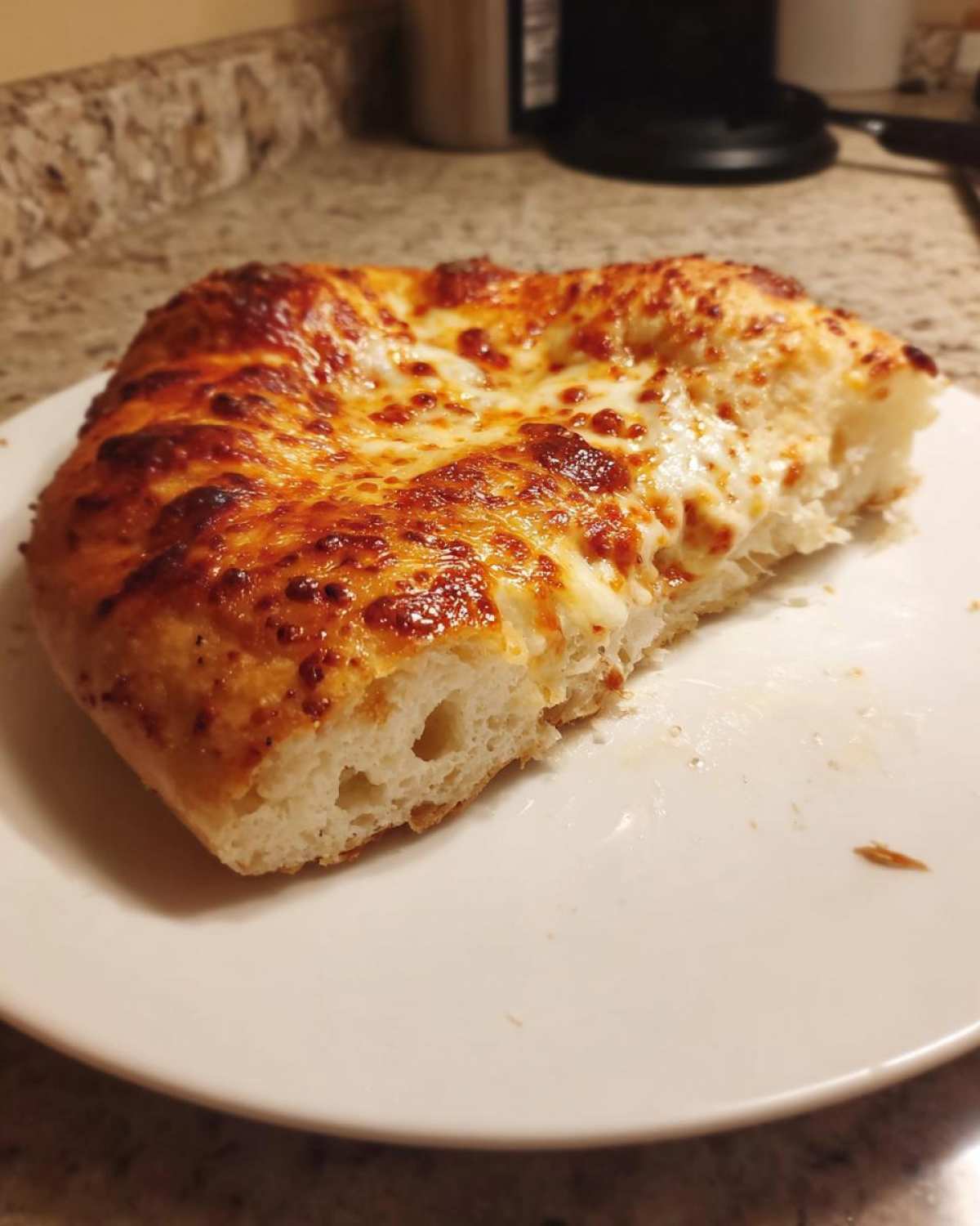 A thick slice of cheesy pizza made with sourdough discard pizza dough, showing a puffy crust.