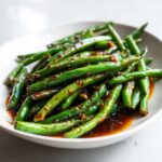 Close-up of vibrant green beans coated in a savory, spicy chinese green beans with garlic sauce.