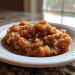 Close-up of chunky, homemade applesauce sprinkled with cinnamon served in a white bowl.