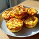 Five golden brown cottage cheese egg cups starbucks style stacked on a white plate.