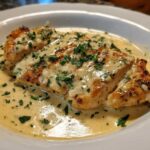 Close-up of pan-seared chicken breasts covered in a rich, creamy lemon chicken sauce and topped with fresh parsley.