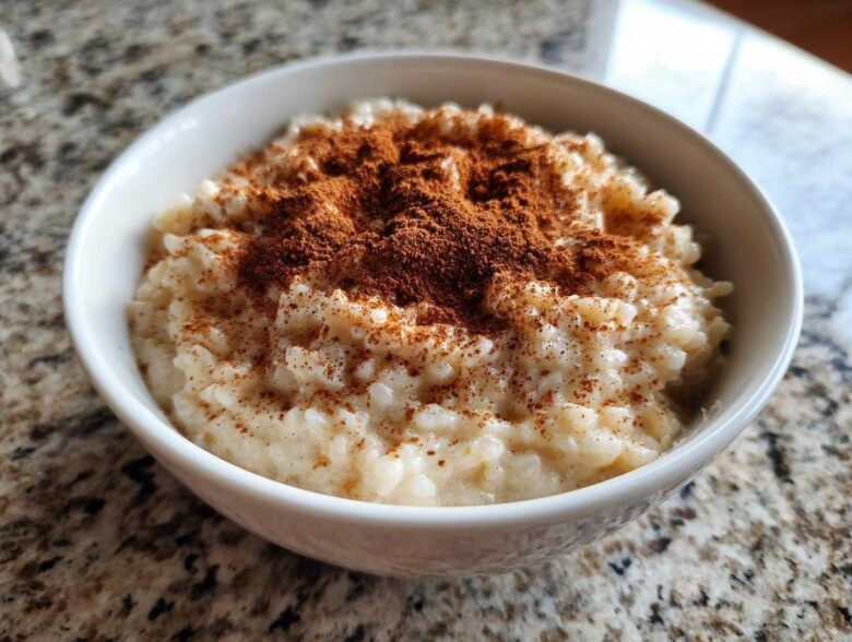 Close-up of creamy rice pudding served in a white bowl, generously dusted with cinnamon.