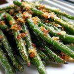 Close-up of bright green beans topped with golden brown, crispy breadcrumbs, highlighting the texture of the green beans.