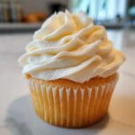 Close-up of a vanilla cupcake topped with perfectly piped, creamy vanilla buttercream frosting.