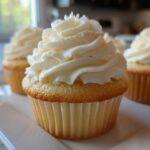 Close-up of a vanilla cupcake topped with perfectly piped, creamy vanilla buttercream frosting.